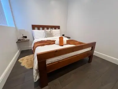 a bedroom with a wooden bed with white sheets at Liverpool Jasmine House - Spacious 2-Bed Near Anfield Stadium in Liverpool