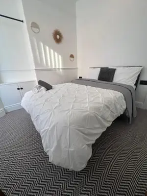 a bedroom with a large bed with white sheets at Liverpool Jasmine House - Spacious 2-Bed Near Anfield Stadium in Liverpool