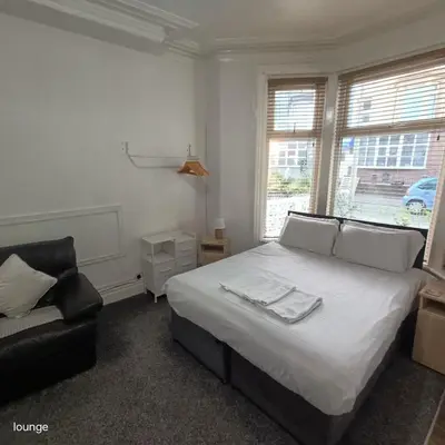 a bedroom with a bed and a chair and a window at Jubilee holiday flats in Blackpool