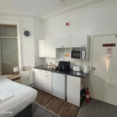 a kitchen with white cabinets and a bed in a room at Jubilee holiday flats in Blackpool
