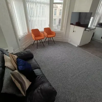 a living room with a couch and two orange chairs at Jubilee holiday flats in Blackpool