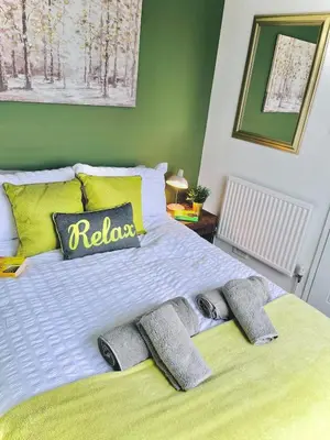 a bedroom with a large bed with yellow and green walls at Lovely 4-bed home sleeps 8 Nr Bolton Stadium & M61 in Blackrod