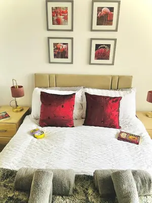 a bedroom with a large bed with red pillows at Lovely 4-bed home sleeps 8 Nr Bolton Stadium & M61 in Blackrod