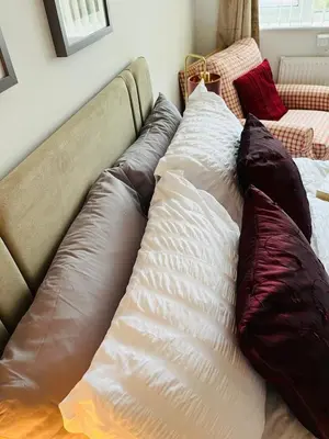 a couch with pillows on top of it at Lovely 4-bed home sleeps 8 Nr Bolton Stadium & M61 in Blackrod