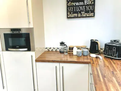 a kitchen with white cabinets and a counter top at Lovely 4-bed home sleeps 8 Nr Bolton Stadium & M61 in Blackrod