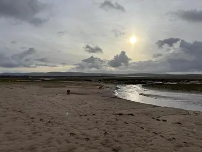 a person walking on a beach with the sun in the sky at 2 Bed in Haverigg oc-s33747 in Haverigg