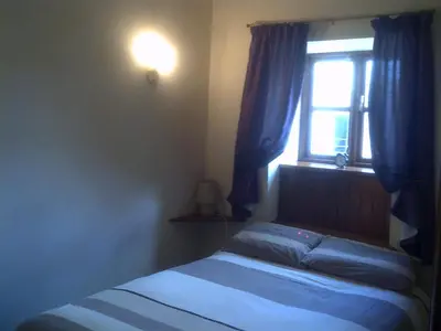 a bedroom with a bed and a window with blue curtains at Knotts Farm Holiday Cottages in Lancaster
