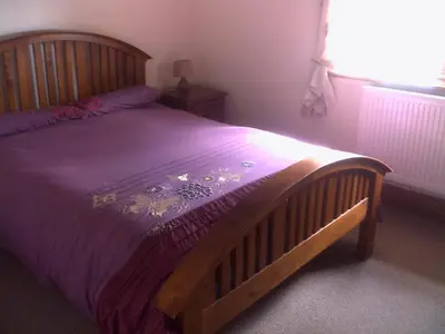 a bedroom with a wooden bed with a purple comforter at Knotts Farm Holiday Cottages in Lancaster