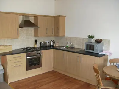 a kitchen with wooden cabinets and a microwave and a table at Knotts Farm Holiday Cottages in Lancaster