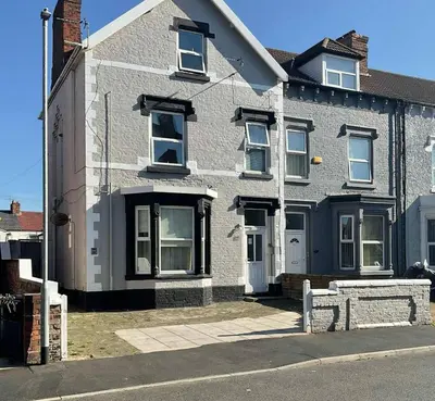 a gray brick house with white windows on a street at MARLEY MANSIONS APARTMENT Clarendon FT3 in Wallasey
