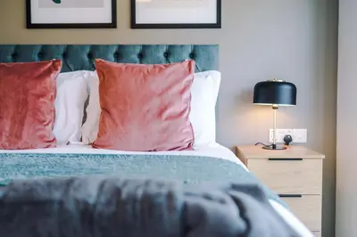 a bedroom with a bed with red pillows and a lamp at High End 2BR 2BA Parking City Access in Liverpool