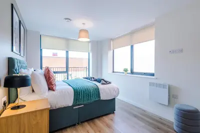 a bedroom with a bed and a desk and windows at High End 2BR 2BA Parking City Access in Liverpool