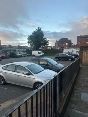 two cars parked in a parking lot next to a fence at Sheridans hotel in Wallasey