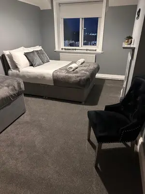 a bedroom with a bed and a chair and a window at Sheridans hotel in Wallasey
