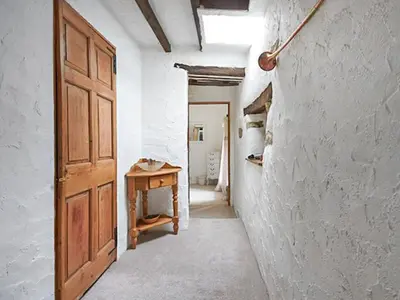 a hallway with a wooden door and a table at Oronsay Cottage in Ulverston
