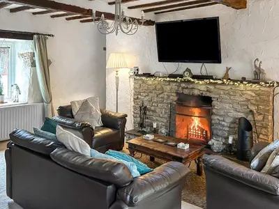 a living room with two leather couches and a fireplace at Oronsay Cottage in Ulverston