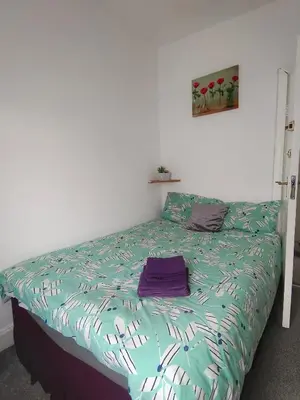 a bedroom with a bed with a purple bag on it at Suncrest Hotel in Blackpool