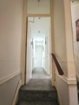 a hallway with a stairway leading to a white door at Suncrest Hotel in Blackpool