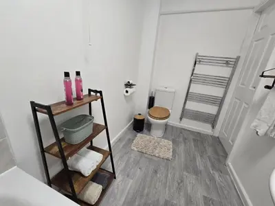 a bathroom with a toilet and a shelf with towels at Room 1 Shared House 3 min from Stadium in Liverpool