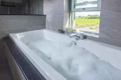 a white bath tub with a sink and a window at Ellenboro House, Cosy Sleeps 2, Near Cartmel in Grange Over Sands