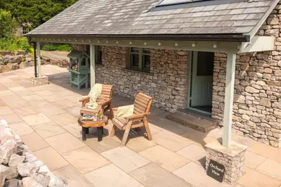 an outdoor patio with two chairs and a house at Ellenboro House, Cosy Sleeps 2, Near Cartmel in Grange Over Sands