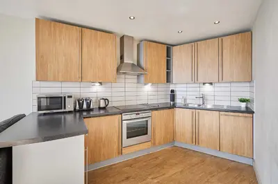 a kitchen with wooden cabinets and stainless steel appliances at Host & Stay - Hatton Garden Apartments in Liverpool
