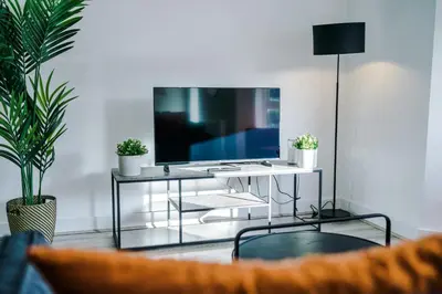 a living room with a television on a white table at Modern 2BR Flat with Parking, Fully Equipped, Sleeps 4 in Liverpool