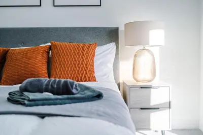 a bedroom with a bed with an orange pillow on it at Modern 2BR Flat with Parking, Fully Equipped, Sleeps 4 in Liverpool