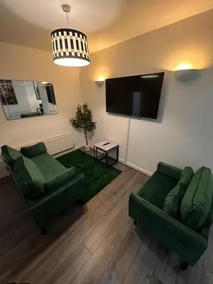 a living room with two green couches and a flat screen tv at Spacious City Centre 2-Bedroom Apartment by StaySavvy Accommodation in Liverpool