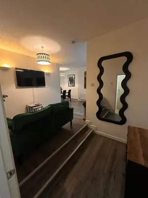 a living room with a green couch and a large mirror at Spacious City Centre 2-Bedroom Apartment by StaySavvy Accommodation in Liverpool