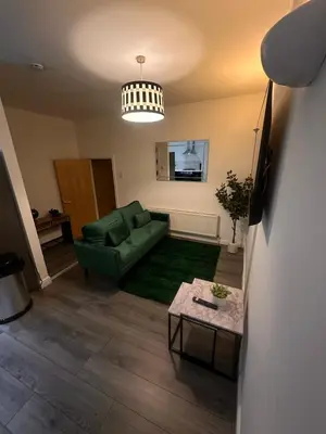 a living room with a green couch and a table at Spacious City Centre 2-Bedroom Apartment by StaySavvy Accommodation in Liverpool