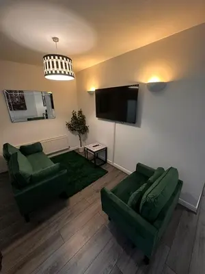 a living room with two green couches and a flat screen tv at Spacious City Centre 2-Bedroom Apartment by StaySavvy Accommodation in Liverpool