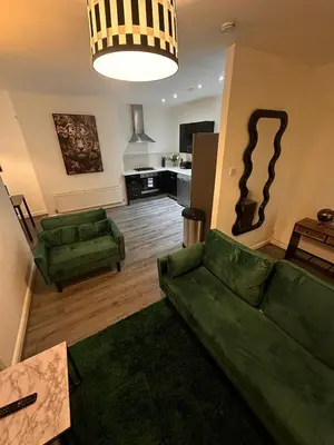 a living room with a green couch and a kitchen at Spacious City Centre 2-Bedroom Apartment by StaySavvy Accommodation in Liverpool