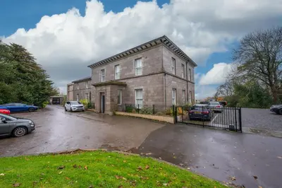 a large brick building with cars parked in a parking lot at Ford Park House Penthouse Escape in Ulverston