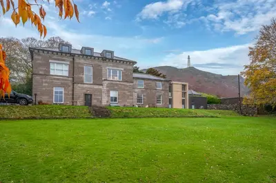 a large brick house with a hill in the background at Ford Park House Penthouse Escape in Ulverston