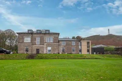 a large brick building with a hill in the background at Ford Park House Penthouse Escape in Ulverston