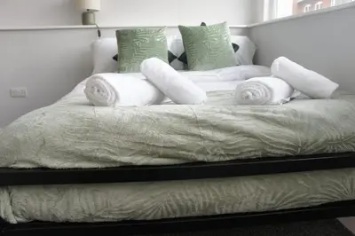 a bed with white blankets and pillows on it at Melbourne House Gem Stylish 2-Bed in City Centre in Accrington