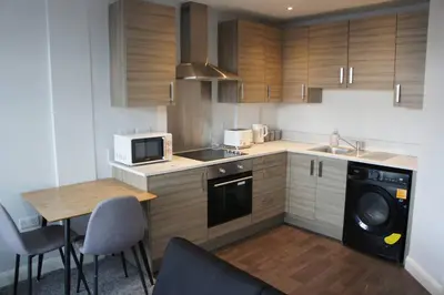 a kitchen with wooden cabinets and a sink and a dishwasher at Melbourne House Gem Stylish 2-Bed in City Centre in Accrington