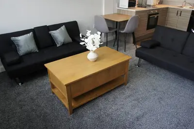 a living room with a couch and a table with flowers on it at Melbourne House Gem Stylish 2-Bed in City Centre in Accrington