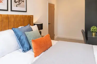 a bedroom with a bed with colorful pillows on it at Modern 3 beds APT, 2 Baths, Free Parking in Liverpool