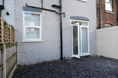 a white brick house with a door and a fence at Antrim House by Serviced Living Liverpool in Liverpool