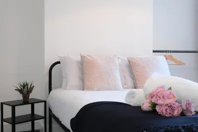 a bed with pink and white pillows and flowers on it at Antrim House by Serviced Living Liverpool in Liverpool