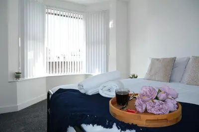 a bedroom with a bed with a tray with flowers on it at Antrim House by Serviced Living Liverpool in Liverpool