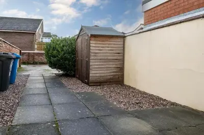 a small wooden shed next to a building at Ribby Stays - 2 bed Cottage Pet Friendly in Wrea Green