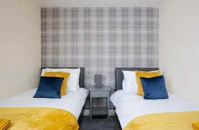 two beds with yellow and blue pillows in a room at Oxheys Stays - Sleeps 7 - Home from Home in Preston