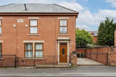 a brick house with a brown door and a fence at Albert Stays - 5 bed Sleeps 11 - Free Parking in Preston