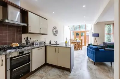 a kitchen with a stove top oven next to a living room at Albert Stays - 5 bed Sleeps 11 - Free Parking in Preston