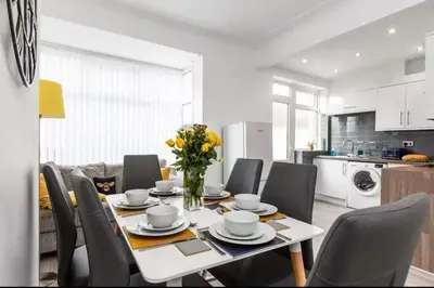 a dining room table with chairs and a vase of flowers at Connaught Stays - Home from Home - Sleeps 7 - Free Wifi in Preston