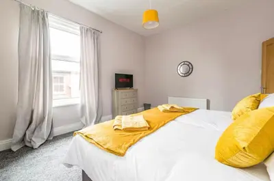 a bedroom with a white bed with yellow sheets and a window at Carnarvon Stays - 2 bed Family Home - Free WiFi in Preston