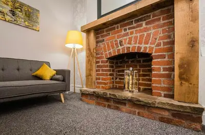 a living room with a couch and a brick fireplace at Carnarvon Stays - 2 bed Family Home - Free WiFi in Preston